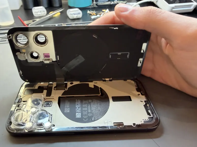 Задня кришка iPhone 15 Pro відкрита, видно акумулятор і камери